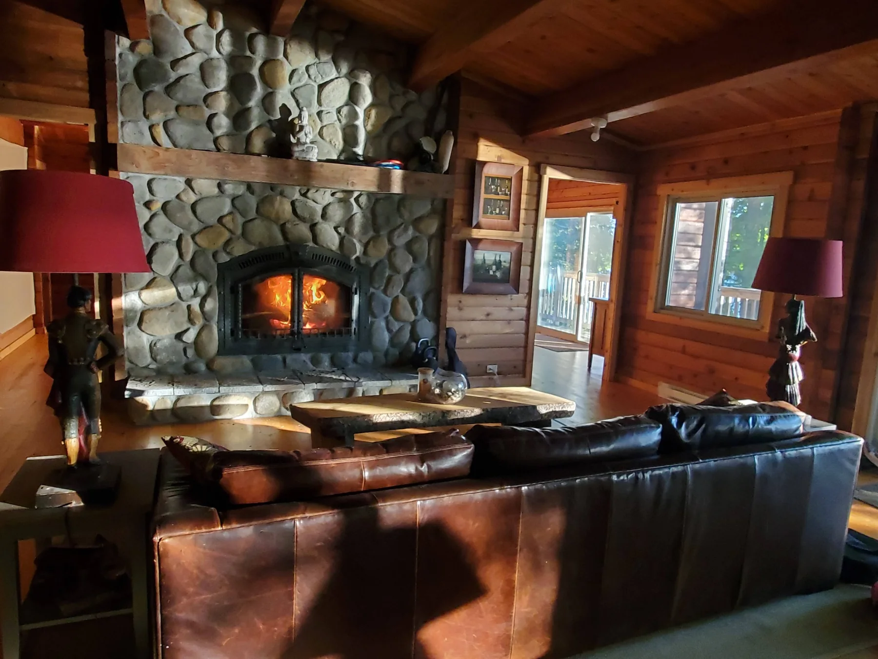 Stone fireplace with a fire burning in the cedar living room